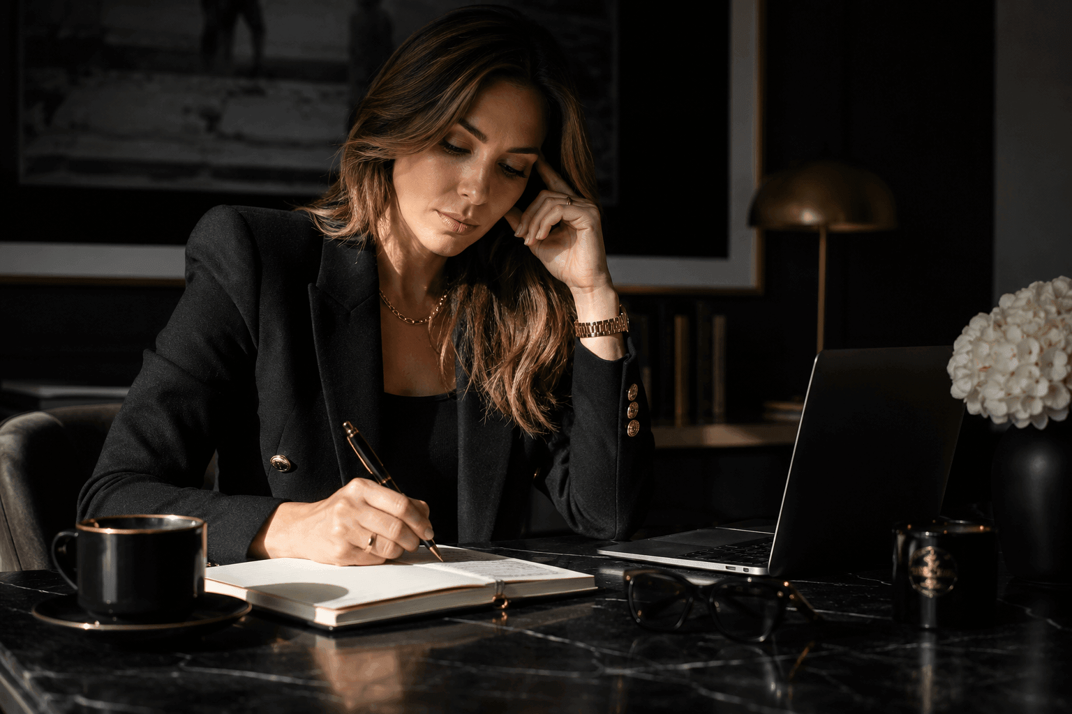 Luxury editorial style feature image showing a sophisticated businesswoman in a dark office writing at a marble desk with a laptop, gold accents, and moody lighting representing focus, execution, and coaching business growth.