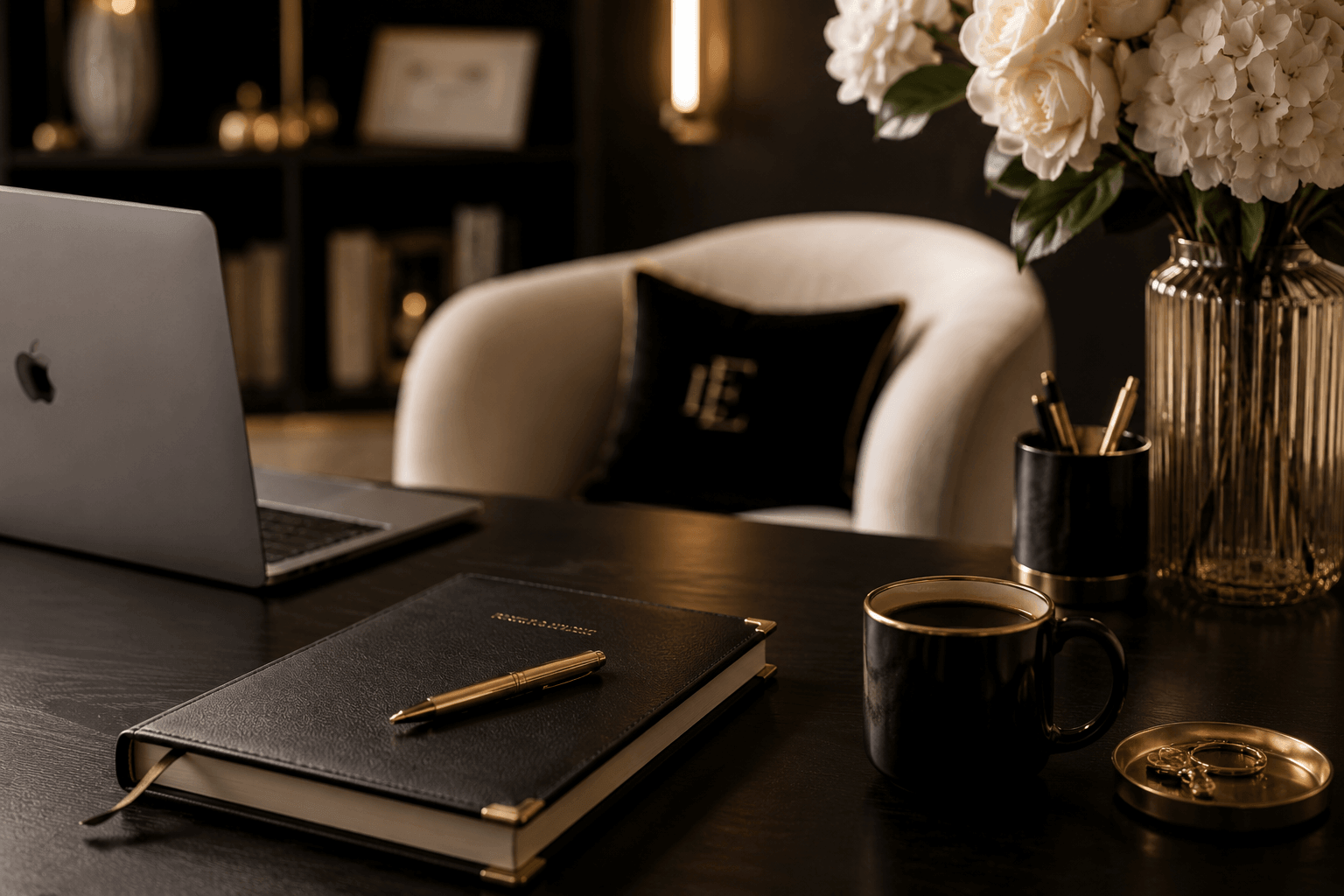Luxury coaching business workspace featuring a black executive desk, gold-accented office accessories, laptop, leather planner, coffee mug, and elegant neutral decor representing financial systems, CEO habits, and consistent income growth for coaches